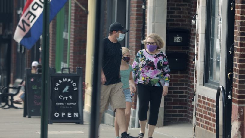 A family all wears masks as they enter a business on Fountain Avenue in Springfield Friday. BILL LACKEY/STAFF