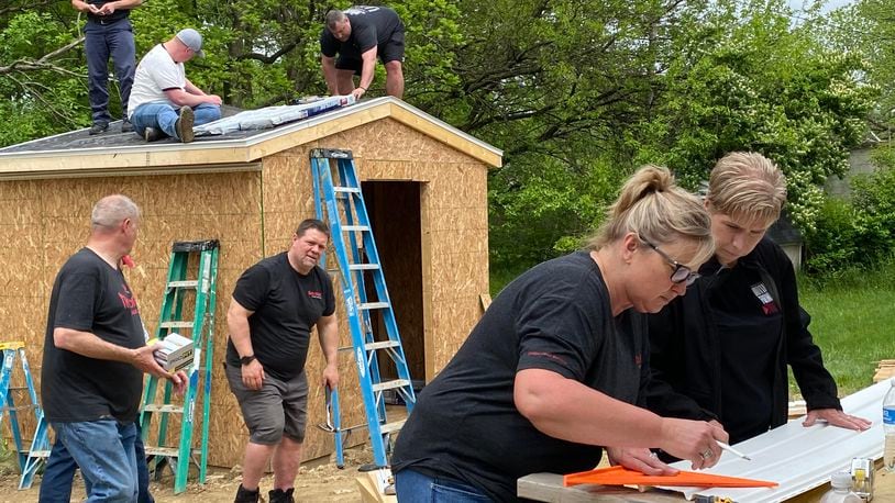 A group of Gordon Food Services volunteers putting on a roof of the shed on Katara Woods' property on West Perrin Avenue, a home that was dedicated to her and her family at the beginning of June. Contributed