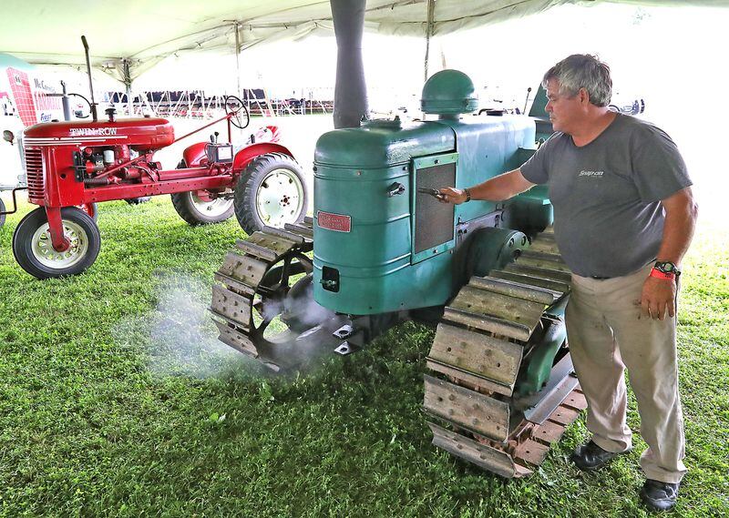 Richard Moore taps a shotgun shell on the side of his Field-Marshall Crawler tractor to start it Friday. The tractor, made in England, required an exploding shotgun shell to start instead of cranking it like most tractors of the day. BILL LACKEY/STAFF