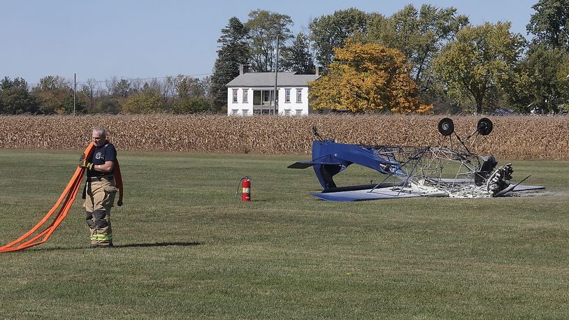 A firefighter collects a firehose after extinguishing a fire that destroyed a single engine airplane when crashed while landing and burst into flames Tuesday at the New Carlisle Airport. The pilot and passenger escaped with non-life threatening injuries. BILL LACKEY/STAFF
