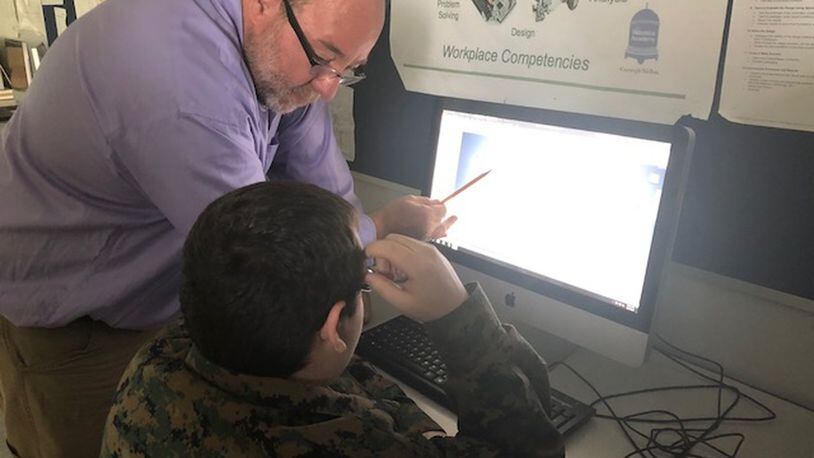 Springfield High School teacher Chuck Stumpf, who worked as an engineer before becoming a teacher, helps a student understand rapid prototyping which is common in engineering and manufacturing fields.