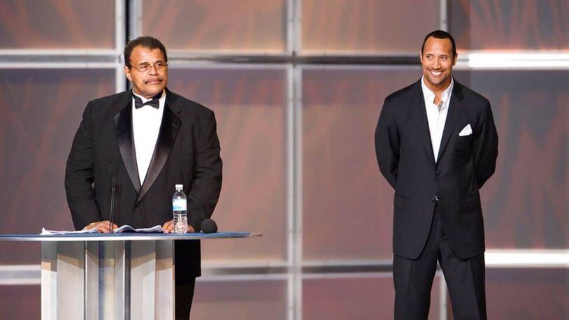 Rocky Johnson, left, speaks after being presented by his son, Dwayne "The Rock" Johnson. for induction into the WWE Hall of Fame in 2008.