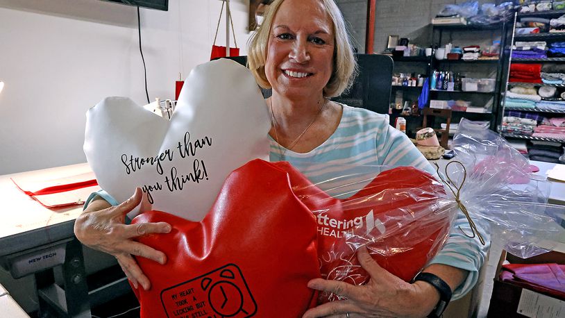 Lynette Evans holds some of her hand made heart pillows, which help people who have had open heart surgery, Wednesday, April 12, 2023 in her workshop. BILL LACKEY/STAFF