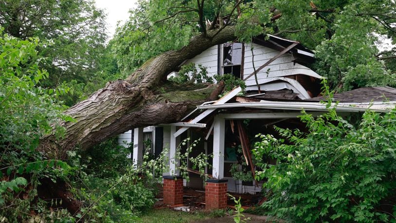 A tree fell on a vacant house on Lincoln Street in Christiansburg in Champaign County on Sunday. Crews were in the village to clean up damage on Monday, June 12, 2023.  BILL LACKEY/STAFF