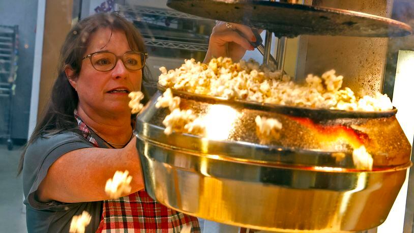 Kathy Brougher, an employee of The Peanut Shoppe, makes fresh popcorn for a customer Tuesday, Nov. 21, 2023. BILL LACKEY/STAFF