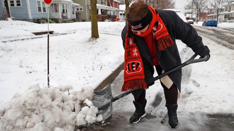 Donna Hall, a diehard Bengals fan, was showing support for her team as she cleaned the slush off Northern Avenue in front of her house so her husband, who works third shift, could have a clean place to park Wednesday morning Jan. 25, 2023, in Springfield. BILL LACKEY/STAFF