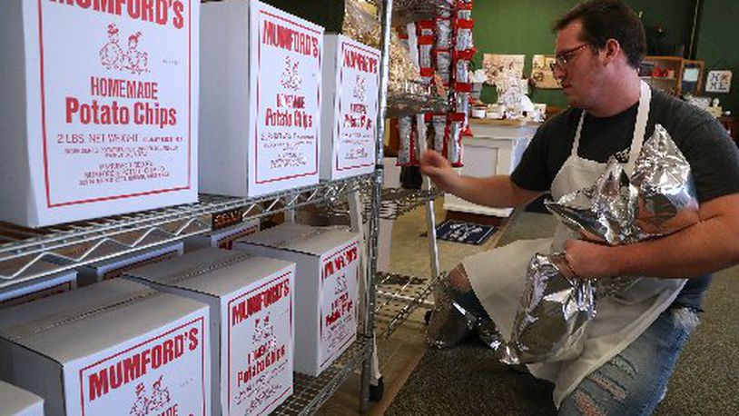 Cody Pack, an employee of Mumford’s Potato Chips, stacks bags of the chips on a shelf. Bill Lackey/Staff