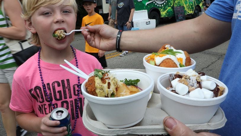 Tate VanHoose, 8, tries some of the food his father, was holding Saturday at the Springfield Rotary Gourmet Food Truck Competition in Veteran’s Park. BILL LACKEY/STAFF