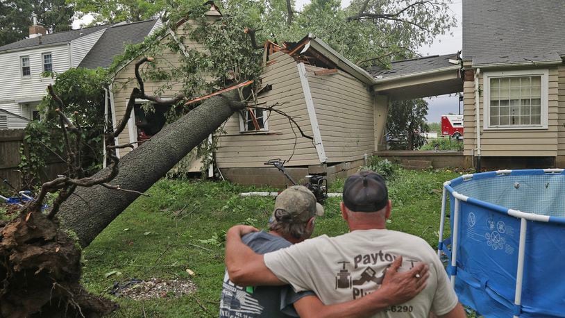 Rob Howard is comforted by his friend Kevin Dancy as they look over the large tree that crushed Howard’s garage  Wednesday, June 8, 2022, in the 2500 block of Mechanicsburg Road near Springfield. BILL LACKEY/STAFF
