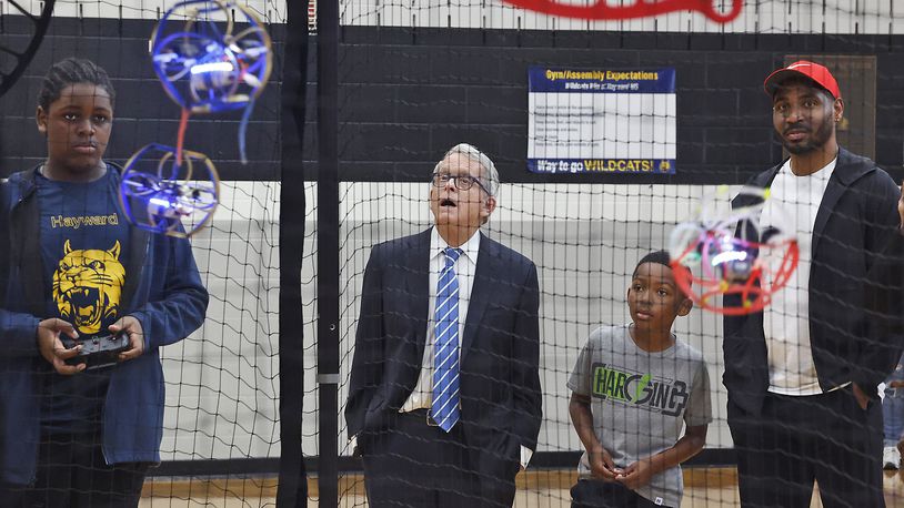 Gov. Mike DeWine and former Ohio State football star Braxton Miller watch as Jamir Rolls, a member of the Hayward Middle School drone soccer team, operates his drone Tuesday, May 7, 2024, in Springfield. The drone soccer team recently returned from Washington, D.C., where they competed in the National Drone Soccer Championships. Hayward was the first school in Ohio to have a drone soccer team. BILL LACKEY/STAFF