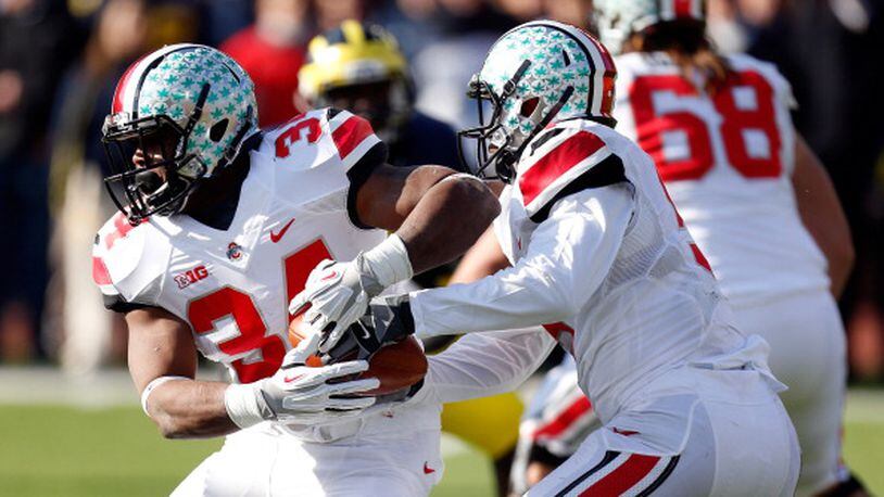 ANN ARBOR, MI - NOVEMBER 30: Quarterback Braxton Miller #5 hands the ball off to running back Carlos Hyde #34 of the Ohio State Buckeyes against the Michigan Wolverines during a game at Michigan Stadium on November 30, 2013 in Ann Arbor, Michigan. (Photo by Gregory Shamus/Getty Images)