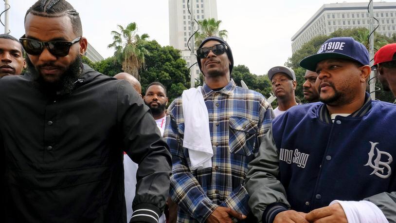 Rappers The Game, left, and Snoop Dogg, center, appear at a peaceful unification march outside of the graduation ceremony for the latest class of Los Angeles Police recruits in Los Angeles, Friday, July 8, 2016. Snoop shook hands with police officials and told reporters he hoped his presence would help reintroduce the black community to the Police Department and open a dialogue. The gathering comes a day after the shooting deaths of multiple police officers in Dallas on Thursday night. (AP Photo/Richard Vogel)