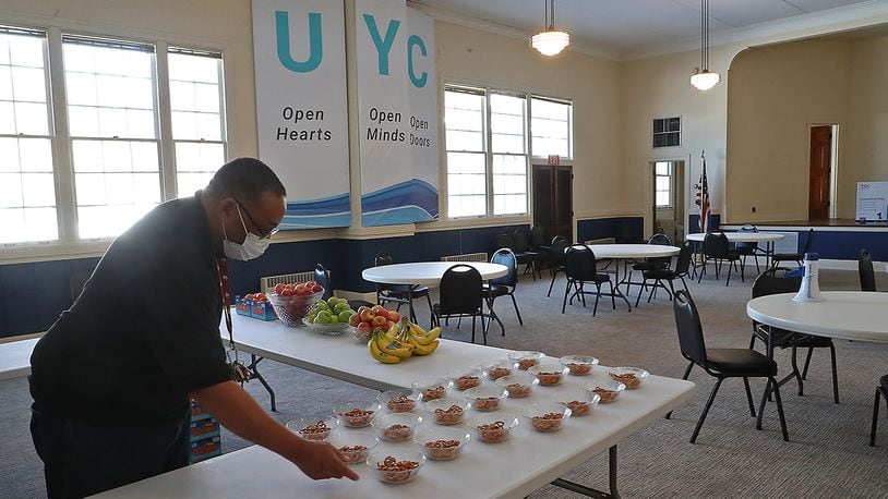 Charles Williams, a voluteer at the Urbana Youth Center, puts snacks out for the young people Tuesday before they arrive after school. BILL LACKEY/STAFF