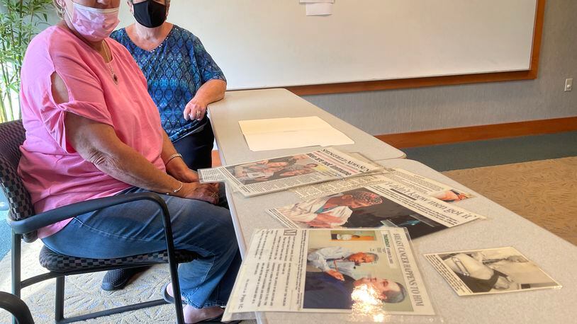 Rhonda Sagraves and Patty Davis look over newspaper clippings detailing the breast cancer diagnosis of Sagraves' husband, Greg, while sitting in the Springfield Cancer Center.