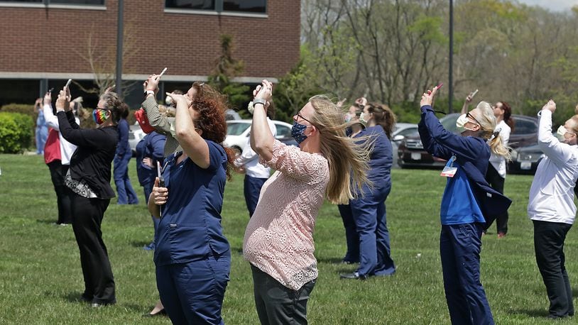 The staff at Mercy Health's Springfield Regional Medical Center gather on the front lawn of the hospital Thursday to watch two Ohio Air National Guard F-16's perform a fly-over as a salute to Ohio health care workers, first responders, military members and other essential personnel. BILL LACKEY/STAFF