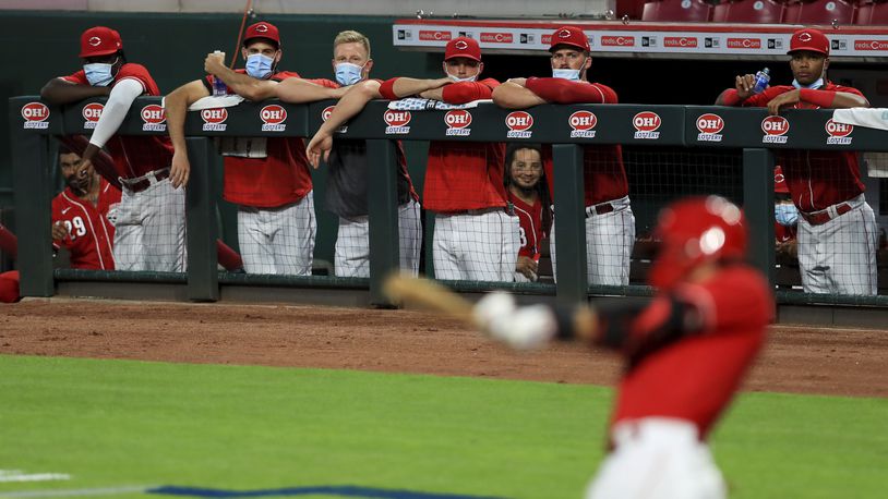 Members of the Cincinnati Reds wear masks as they watch the game from the dugout during an exhibition baseball game against the Detroit Tigers at Great American Ballpark in Cincinnati, Tuesday, July 21, 2020. The Reds won 9-7. (AP Photo/Aaron Doster)