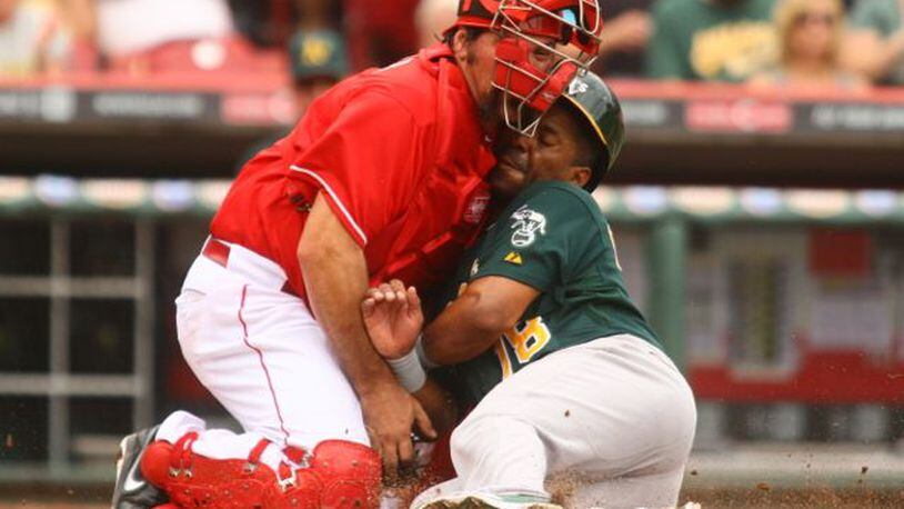 Reds catcher Corky Miller tags out the A's Alberto Callaspo as they collide at home after a throw from Jay Bruce in the fourth inning on Wednesday, Aug. 7, 2013, at Great American Ball Park in Cincinnati. David Jablonski/Staff