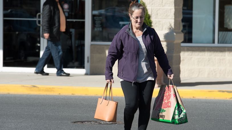 A shopper carries her bags to her car at Tanger Outlets Surfside location in Rehoboth.