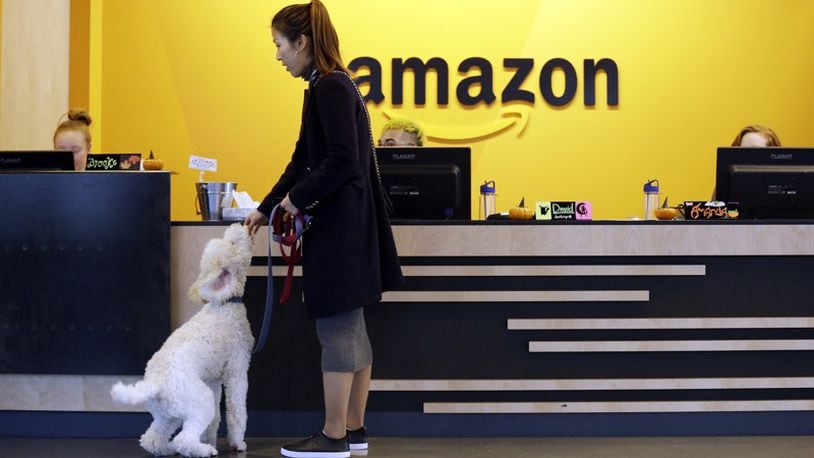 In this Wednesday, Oct. 11, 2017, photo, an Amazon employee gives her dog a biscuit as the pair head into a company building, where dogs are welcome, in Seattle. Amazon says it received 238 proposals from cities and regions hoping to be the home of the company’s second headquarters. The online retailer kicked off its hunt for a second headquarters in September, promising to bring 50,000 new jobs. It will announce a decision sometime in 2018. (AP Photo/Elaine Thompson, File)