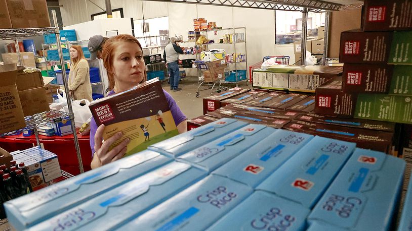 Maggie Yontz stocks the shelves of the food pantry with cereal Monday, Dec. 5, 2022 at the Second Harvest Food Bank. BILL LACKEY/STAFF