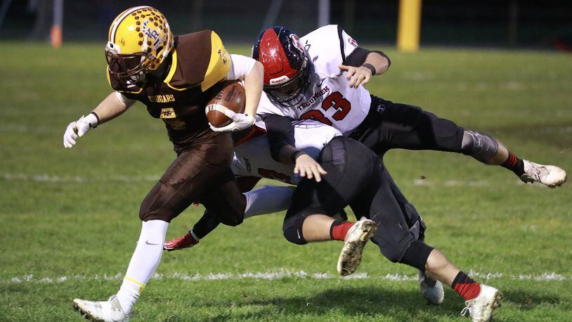 Kenton Ridge’s Zach Schneider gets knocked out of bounds by Tecumseh s Ryan Rowland and Caleb Edwards as he carries the ball. Bill Lackey/Staff