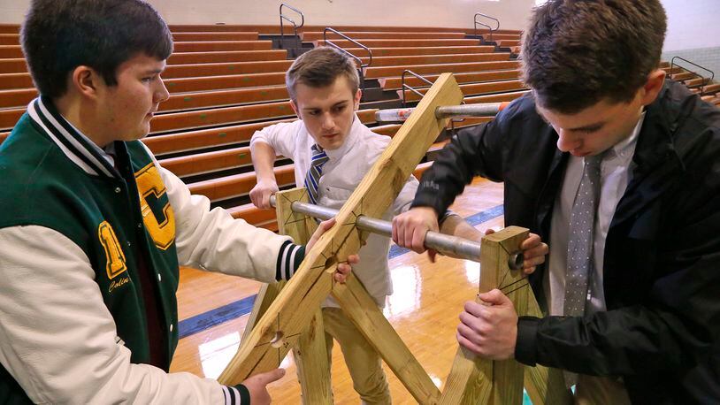 Catholic Central High School junior’s, from left, Colin Hanna, Sean Alexander and Jack Brougher assemble a trebuchet which they made for their engineering class. Bill Lackey/Staff