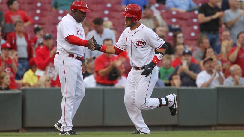 The Reds’ Eugenio Suarez, right, slaps hands with third-base coach Billy Hatcher after a home run against the Brewers on Tuesday, June 27, 2017, at Great American Ball Park in Cincinnati.