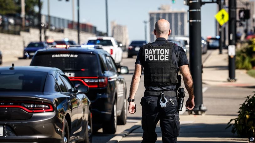 A Dayton police officer walks up Main Street toward Miami Valley Hospital as Richmond, Indiana, and Dayton police cruisers line the street Thursday, Sept. 1, 2022. Richmond officer Seara Burton, shot Aug. 10 in the line of duty, was to be taken off life support. JIM NOELKER/STAFF