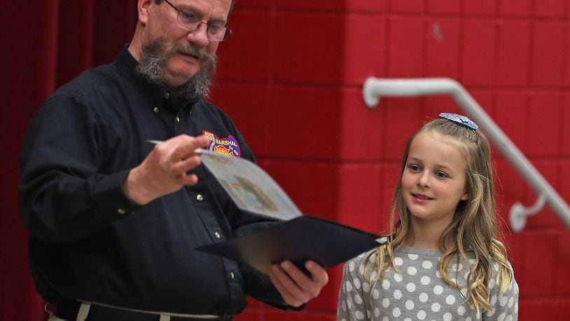 Piper Burcham, a third grader at Snowhill Elementary, is presented with an award by Charles Arnold, from the State Marshall’s Office, for her fire awareness poster she made for their annual contest. Piper is one of 12 students in the state to receive an award for her poster. BILL LACKEY/STAFF