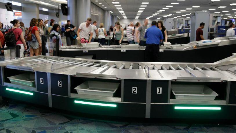 In this Sept. 1, 2017, photo, people use newly installed automated security lanes at McCarran International airport Friday, Sept. 1, 2017, in Las Vegas. Three reconfigured security lanes are equipped with upgraded features, including bins that are 25 percent larger and capable of holding roll-aboard luggage.
 (AP Photo/John Locher)