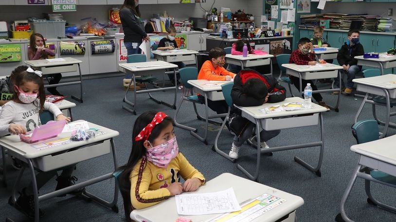 INITIAL CUTLINE: With masks and desks spaced apart, students at Simon Kenton Elementary work on classwork Friday, Feb. 19, 2021.