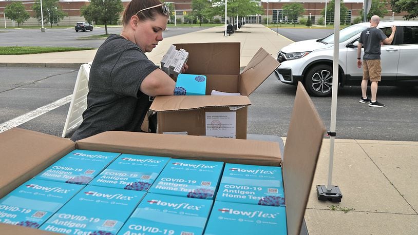 Stephanie Johnson and Chris Cook, from the Clark County Combined Health District, pass out COVID-19 home test kits in a drive-thru Tuesday, June 7, 2022 in the parking lot at Springfield High School. BILL LACKEY/STAFF