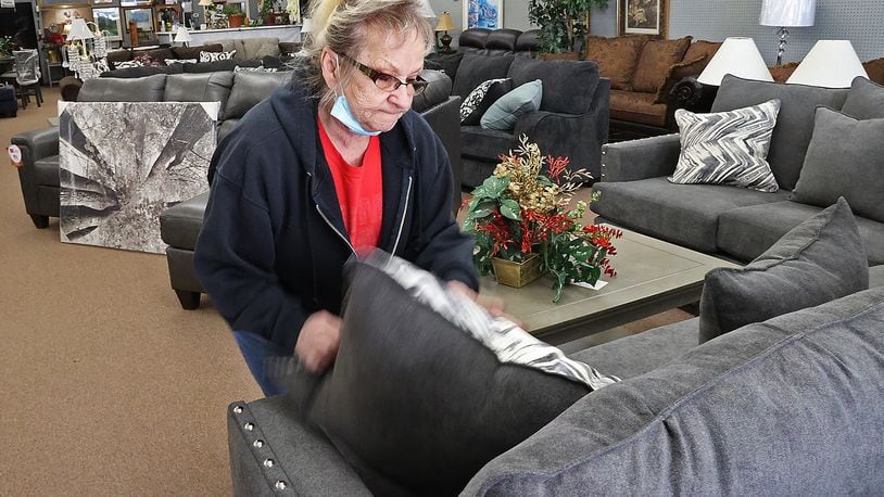 Sue Call, owner of Sue's Furniture in Springfield, fluffs the pillows on a sofa in her showroom Tuesday. BILL LACKEY/STAFF