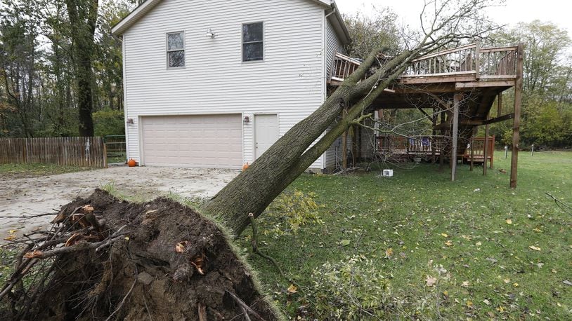 A tree rests on the second story of a deck attached to a house along Long Court in South Vienna Monday. Bill Lackey/Staff