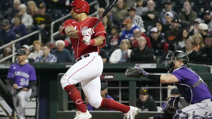 Cincinnati Reds' Christian Encarnacion-Strand, left, follows through on a swing on his infield single as Colorado Rockies catcher Brian Serven, right, looks on during the second inning of a spring training baseball game, Monday, March 6, 2023, in Goodyear, Ariz. (AP Photo/Ross D. Franklin)