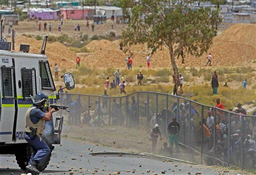 A South African policeman. left, fires a rubber bullet, at striking farm workers.