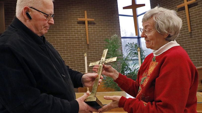 Jan Kushmaul, a member of the Highlands United Church of Christ, gives gives the cross from the alter in the church’s sanctuary to Rev. Dr. Robert Smitley, the chaplain at the Patriot Ridge Community in Fairborn, Wednesday. Jan was giving Dr. Smitley items the church would not need after this weekend when they close. Bill Lackey/Staff