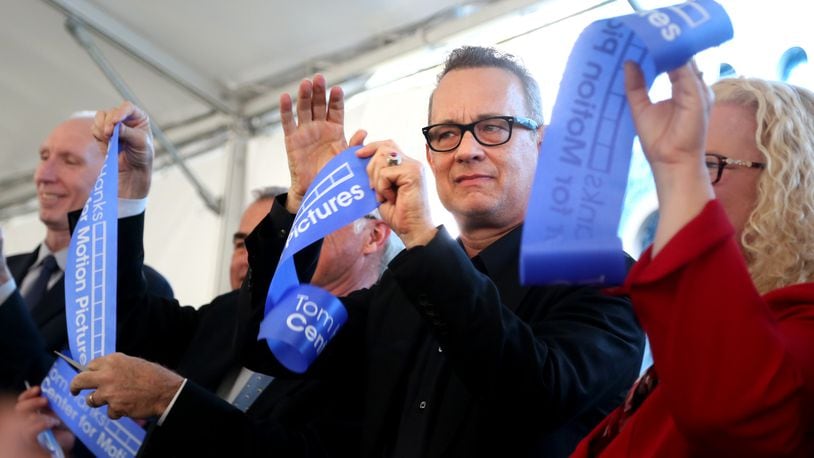 Actor Tom Hanks holds up a piece of cut ribbon after participating in a ribbon cutting for the new Tom Hanks Center for Motion Pictures at Wright State University Tuesday. LISA POWELL / STAFF