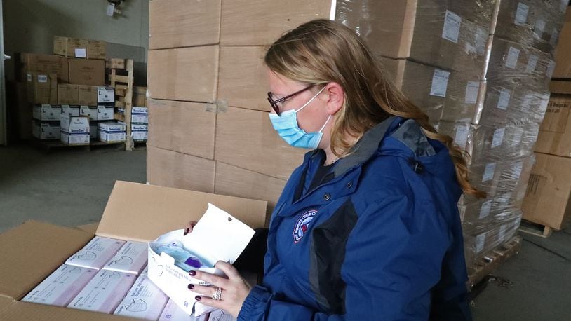 Michelle Clements-Pitstick, director of the Clark County EMA, opens up one of the cases filled with thousands of masks that they will distribute in the county to try and slow down the rise in COVID-19 cases in the county. BILL LACKEY/STAFF
