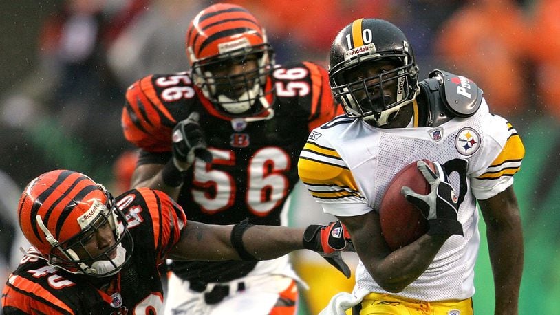 CINCINNATI - DECEMBER 31: Santonio Holmes #10 of the Pittsburgh Steelers eludes Madieu Williams #40 of the Cincinnati Bengals en route to a touchdown in overtime on December 31, 2006 at Paul Brown Stadium in Cincinnati, Ohio. The Steelers defeated the Bengals 23-17. (Photo by Matthew Stockman/Getty Images)