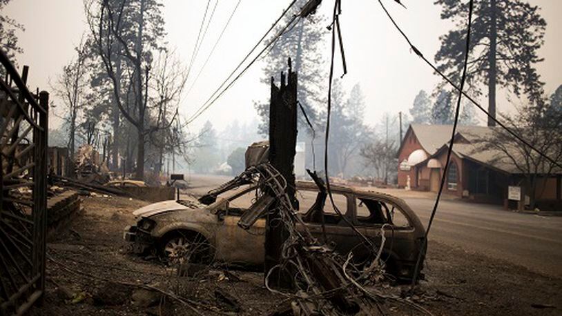Burnt wreckage remains on Tuesday, Nov. 13, 2018, across the street from structures left unscathed by the Camp Fire in Paradise, Calif. Search teams were heading back into the devastated town on Tuesday with the grim expectation of finding more bodies in the charred remnants of the Sierra Nevada retirement community. (Jenna Schoenefeld/The New York Times)