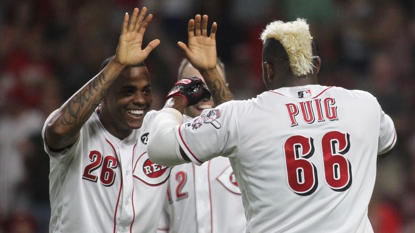 The Reds’ Raisel Iglesias, left, slaps hands with Yasiel Puig after a victory against the Brewers on Tuesday, July 2, 2019, at Great American Ball Park in Cincinnati. David Jablonski/Staff