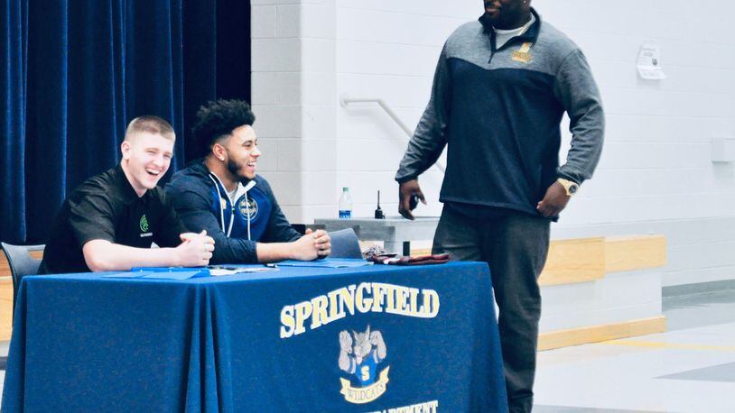 Springfield High School seniors Zack Breslin (let) and Tavion Smith (center) share a laugh with linebackers’ coach C.J. Peake before the start of a signing day ceremony at the school, Feb. 6, 2019. Nick Dudukovich/CONTRIBUTED