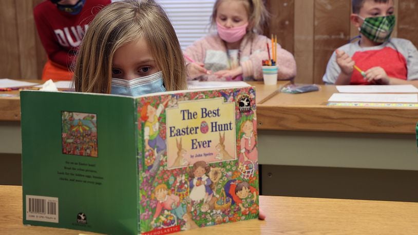 A first grade student reads a book after finishing her classwork at The Village. BILL LACKEY/STAFF