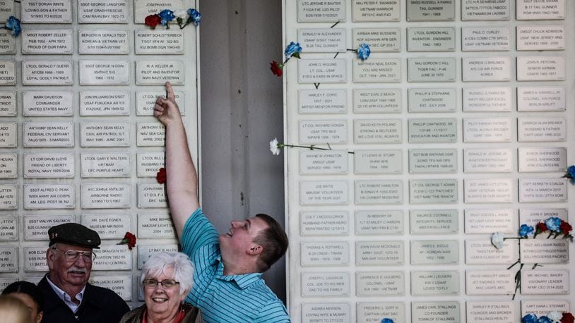 Ash Williams from New Madison points up at his Great Grandfathers, WWII veteran Robert Schlotterbeck's plack.  
The Air Force Museum held its first Honor Plate Ceremony since the pandemic three years ago. A total of 475 new names were added to the wall. After the ceremony, family and friends hung flowers near their loved one's plates. JIM NOELKER/STAFF