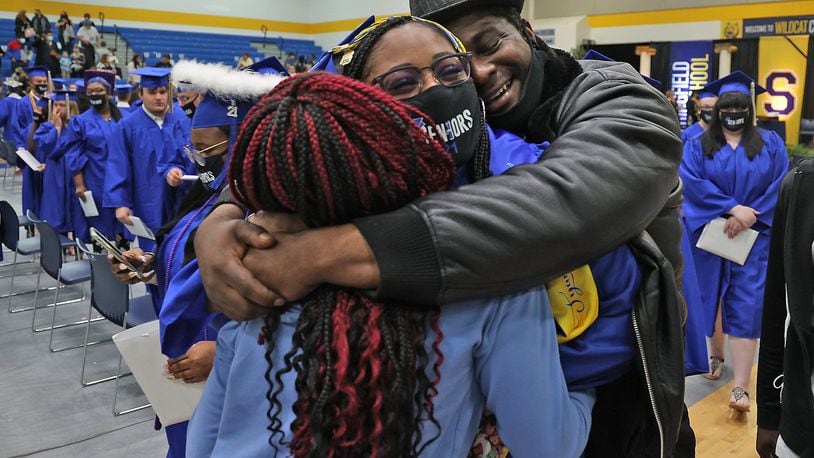 Springfield High School graduate Tyana Crossley is hugged by her father, Mitchell, and sister, Zayveana, after they rushed the floor as the graduates were marching out of the gymnasium Saturday. In an effort to keep crowds small, Springfield held three graduation ceremonies on Saturday. BILL LACKEY/STAFF
