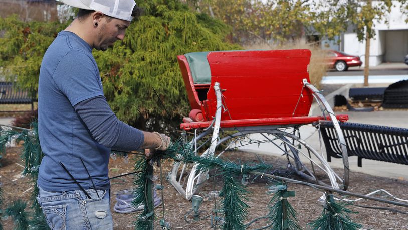 Derek Snowden, from InDistress, attaches holiday lights a garland to a wire frame as he creates a spot on the Springfield City Hall Plaza for holiday photos Wednesday, Nov. 9, 2022. The sleigh and photo spot are part of the Holiday in the City events that will run from Friday through the New Year holiday. BILL LACKEY/STAFF
