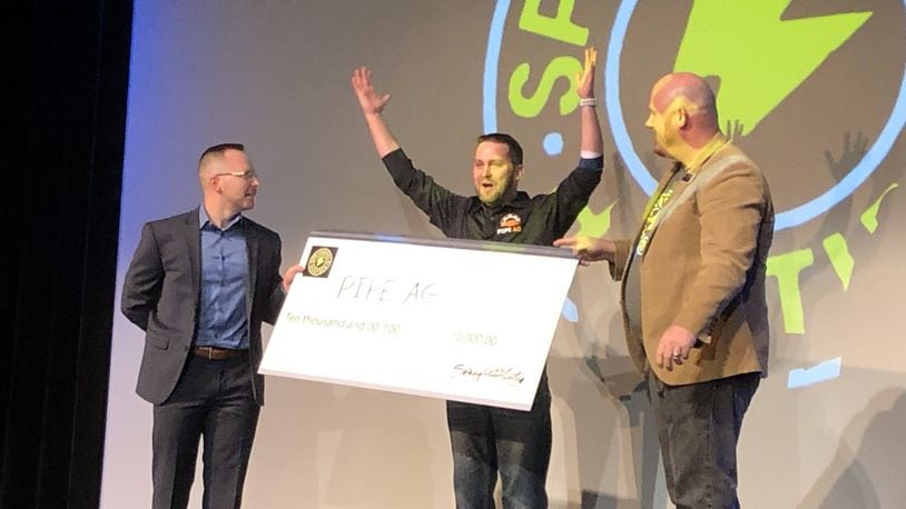 Roark Thompson of PIPE Ag celebrates winning the first Springfield Hustles grand prize with a check offered by Blake Shaffer, left, and Rob Alexander at the John Legend Theater on Wednesday. Photo by Brett Turner