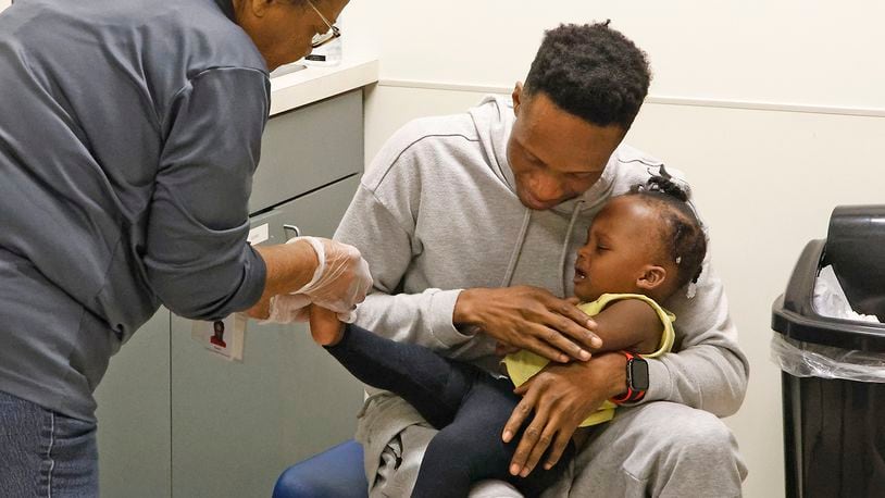 Roody Toussaint comforts his daughter, Mary Woodarline Toussaint, as nurse Susan Cole draws a drop of blood from her foot Monday, Oct. 16, 2023 at the Clark County Combined Health District's WIC program office. BILL LACKEY/STAFF