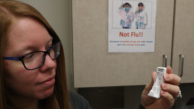 Keli Criner, a pediatric nurse at the Rocking Horse Center, checks for a possitive test for the flu virus Wednesday. BILL LACKEY/STAFF